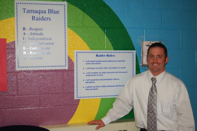 JOE PLASKO/TIMES NEWS Tamaqua Area Assistant Elementary Principal James J. Fasnacht displays signs for the Raider Rules code of conduct implemented in the school district's three elementary schools this year.