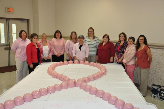 AMY ZUBEK/TIMES NEWS Organizers of the Fifth Annual Horizon of Hope luncheon gather around a pink breast cancer awareness ribbon, made out of Longaberger measuring cups, to show their support of Jessyca Fredericks, center, who is currently battling…