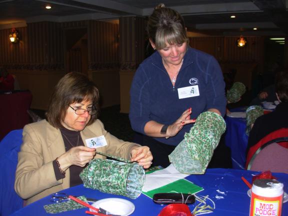 ADELE R. ARGOT/SPECIAL TO THE TIMES NEWS Jeannie Hartenfels, left, paints mod-podge on her glass candle vase and places the decorative design on it under the tutelage of Kathy Lombardo of Neola. It was her first time at the annual holiday program…
