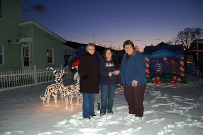 Gail Maholick/TIMES NEWS Lynette Moyer, center, accepts a check of $100 for having the first place display in the Concerned Citizens of Weissport Christmas Light display. Presenting the checks are Linda Schoenberger, left; and Tammy Solt, right.
