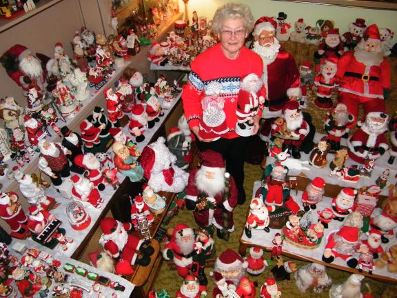 ANDREW LEIBENGUTH/SPECIAL TO THE TIMES NEWS Erma Warne of New Ringgold stands in the middle of her parlor surrounded by hundreds and hundreds of Kriss Kringles. She holds the first animated Santa and Mrs. Claus she purchased almost 20 years ago.