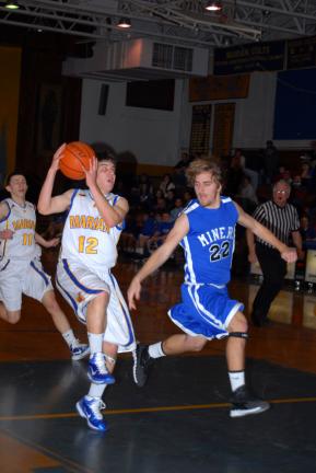 RON GOWER/TIMES NEWS Marian Catholic's Ryan Karnish (12) drives past Zach Dixon of Minersville. Karnish was the high scorer for the Colts with 10 points, including two three-point baskets.