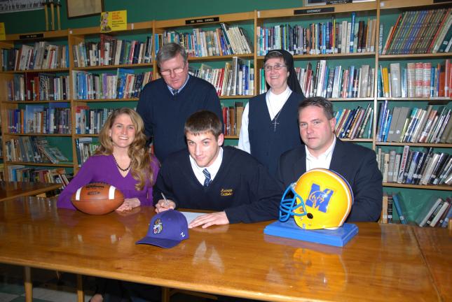 Ron Gower/TIMES NEWS Marian's Dominick Richards, center, signs letter committing himself to James Madison University. Seated with him are his parents, Jeanette and Ralph Richards. Looking on are his high school football coach Stan Dakosty and the…