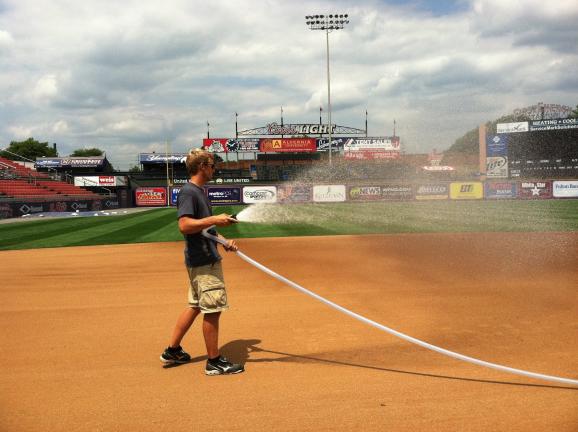 Travis Pitts hoses down the infield before a recent Reading Phillies game. Pitts, a Tamaqua High School graduate and current star member of the Delaware Valley College track team, is doing an internship with the R-Phils this summer.
