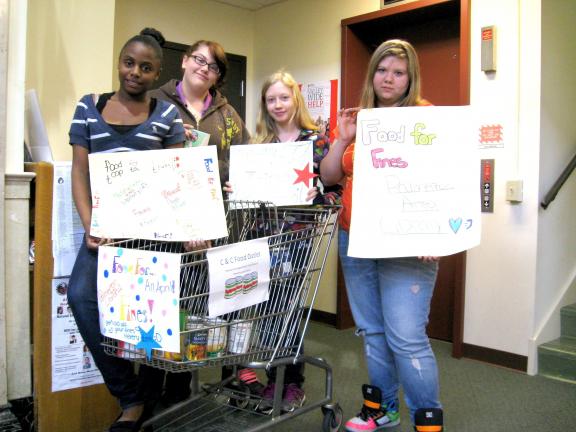 STACEY SOLT/SPECIAL TO THE TIMES NEWS Members of the Teen Advisory Group at the Palmerton Area Library show the "Food for Fines" signs they recently created. During the month of April, the Palmerton Area Library will waive $1 off members' overdue…