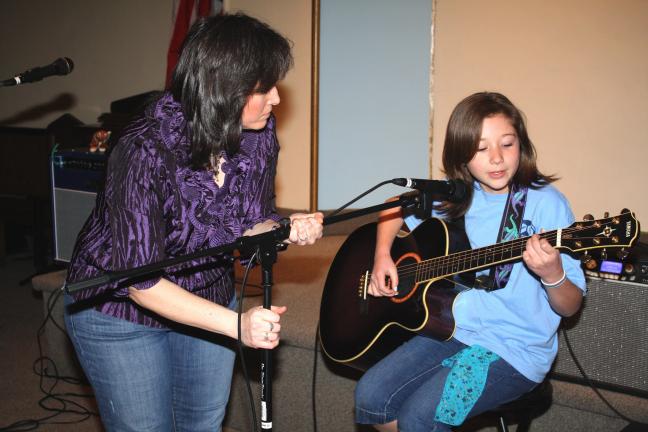 ANDREW LEIBENGUTH/TIMES NEWS Center volunteer Kathy Rimm fixes the microphone so young talent Faith Roberts, 14, of Tamaqua, can perform a vocal guitar solo.
