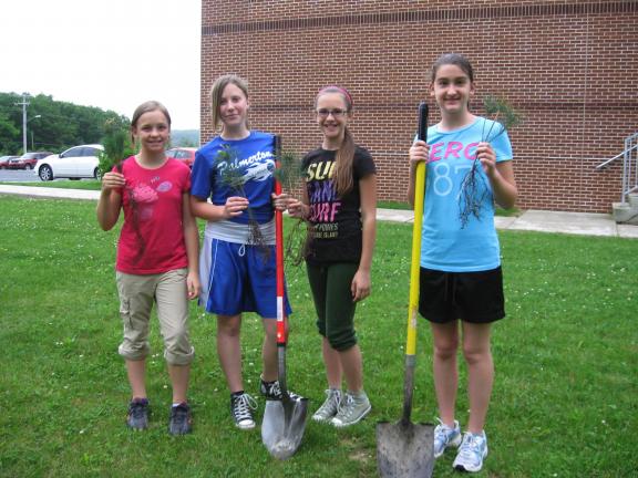 STACEY SOLT/SPECIAL TO THE TIMES NEWS ABOVE: Cadette Girl Scouts Lindsey Shimko, left, Skye Klotz, Madison Wenig, and Holly Ahner prepare to plant trees at Towamensing Elementary School. The Scouts from Palmerton Troop 37 planted trees as part of…