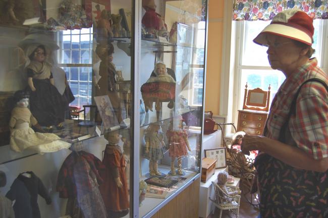 Joan Deering looks at the dolls in a cabinet. She especially like a three-wheeled doll carriage.