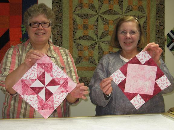 STACEY SOLT/SPECIAL TO THE TIMES NEWS @$:Quilted Crow co-owners Jane Heckman, left, and Cindy Mengel-Smith show the blocks that will be used in the store's "Quilting Pink for a Cure" project. Local quilters are asked to purchase a block kit for $5 …
