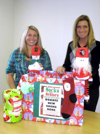 STACEY SOLT/SPECIAL TO THE TIMES NEWS Jessica Kutza, left, and Mary Ann Dulaney show a "Socks for Seniors" drop-off box. The mother-daughter team is organizing a gift drive for local senior citizens through the national "Socks for Seniors" program,…