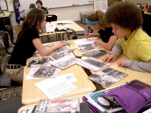 From left are Skylar Francesco, McKenzie Lazar and Crystal Nase as they examine several Civil War era photographs during the Traveling Trunk program at Panther Valley Middle School.