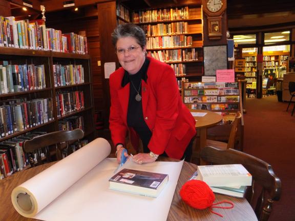 STACEY SOLT/SPECIAL TO THE TIMES NEWS Dimmick Memorial Library director Susan Sterling prepares a book for the library's "blind date with a book" program. Readers can choose from a variety of mystery books, each wrapped in brown paper with a short…