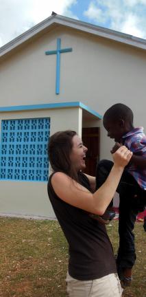 SPECIAL TO THE TIMES NEWS Misericordia University occupational therapy student Debbie Keys of Jim Thorpe, enjoys a playful moment with a child outside St. Joseph's Church in Jamaica.