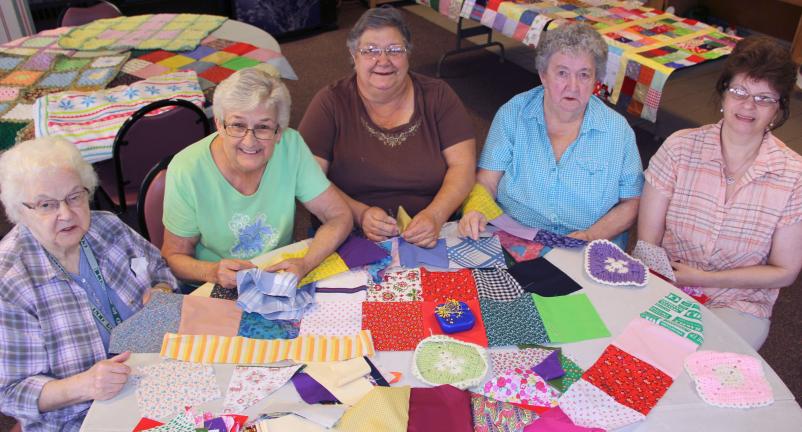 TOP: Members of the Happy Hookers are, from left, Nancy Hartz, Connie Dixon, Doris Nelson, Janet Hagerty and Laurie Wall. Other members include Maryann Lishman, Peggy McArdle and Bonnie Smith. ABOVE: Showing off their work are members Connie Dixon…