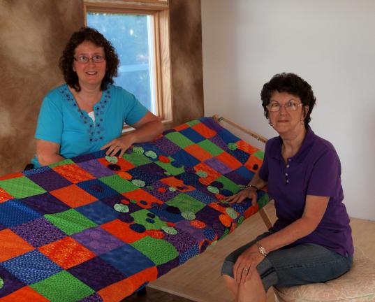 AL ZAGOFSKY/SPECIAL TO THE TIMES NEWS Lisa Krouse (left) Claudette Gosselin, two of the Mahoning Valley Fiber Guild founders with a quilt made by Krouse, a former arts teacher. The quilt features "yo-yos" pieces of circular fabric that are drawn in,…