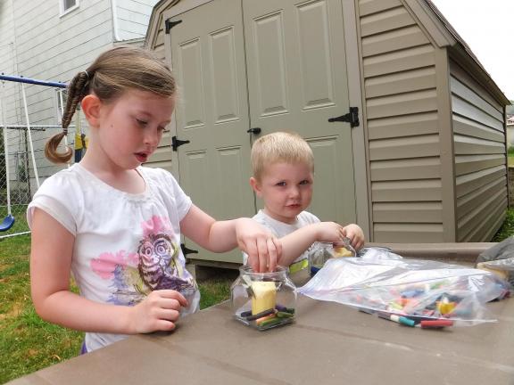STACEY SOLT/TIMES NEWS Zoe Rodgers, 4, and Andrew Rodgers, 3, make crayon candles on a hot summer day. The craft was part of a lesson on the sun as the sun heated the crayons, they melted to create a colorful candle.