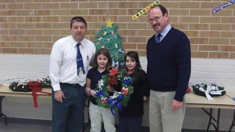 SPECIAL TO THE TIMES NEWS Henry Desrosiers, director of the Carbon County Veterans Affairs office, right, accepts a homemade wreath from Annabella Redline and Dakota Naimon, two students from the fourth-grade class of Leo O'Donnell, left. Annabella…