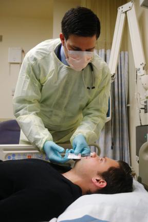 AP PHOTO Live flu virus is sprayed into the nose of Daniel Bennett, 26, of College Park, Md., who is part of a study at the National Institutes of Health in Bethesda, Md.