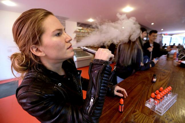 In this Feb. 20, 2014 photo, Talia Eisenberg, co-founder of the Henley Vaporium, uses her vaping device in New York. The vaporium is an intimate hipster hangout in the Soho neighborhood with overstuffed chairs, exposed brick, friendly counter help,…