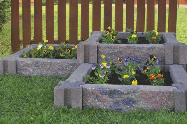 Courtesy of Infinity Lawn and Garden Incorporating raised flower beds using stone planters can beautify the landscape without taking a lot of time or effort.