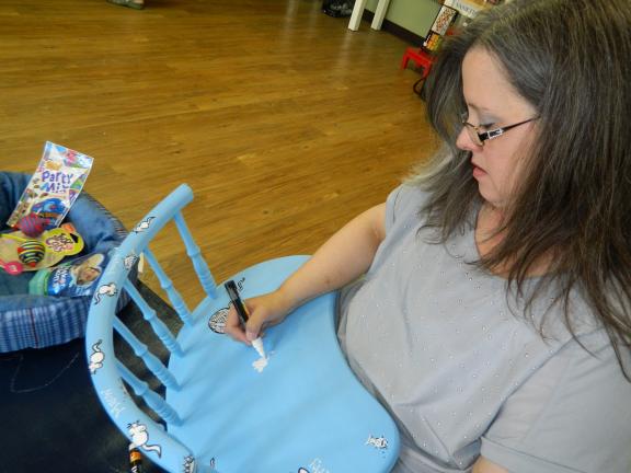 Sandi Winter finishes one of the four chairs she donated to the Penn Kidder Library Center Chair-ity auction. Winter loves arts and crafts and repurposing these old and broken chairs was just the sort of project that she enjoys.