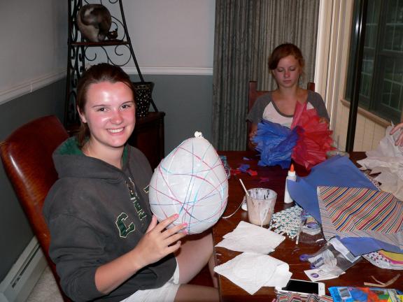 This Thursday, July 3, 2014 photo shows Hope Clarke, 16, left, as she wraps yarn soaked in craft glue around a balloon while Hadley Hagemann, 16, works on a giant tissue pom-pom at a crafting night hosted at Clarke's house in Arvada, Colo. After the…
