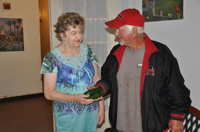 AMY MILLER/TIMES NEWS Suopira, left, takes cucumbers that she purchased from Richard Graver, owner of Graver's Orchard in Lehighton, at the Panther Valley Senior Center in Nesquehoning recently.