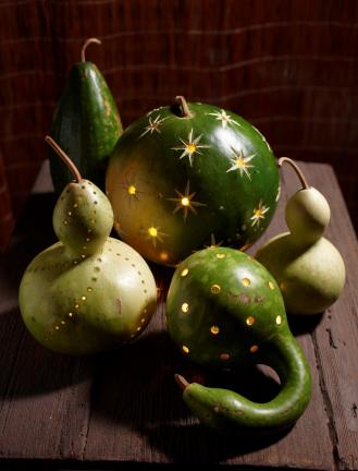 In this undated photo provided by Better Homes and Gardens, lighten up Halloween night with luminaries. Do-it-yourself projects include drilling gourds and pumpkins with random holes or in a pattern then inserting battery-operated votives. Cut a…