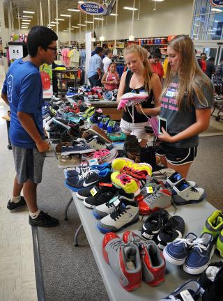 FILE - In this Wednesday, Aug. 5, 2015, file photo, Ramon Gonzalez, left, Martha McDonald and Kayla Wilkes, right, shop for shoes at Academy Sports and Outdoors, in Wichita Falls, Texas. To get the best back-to-school deals, experts say it's all in…