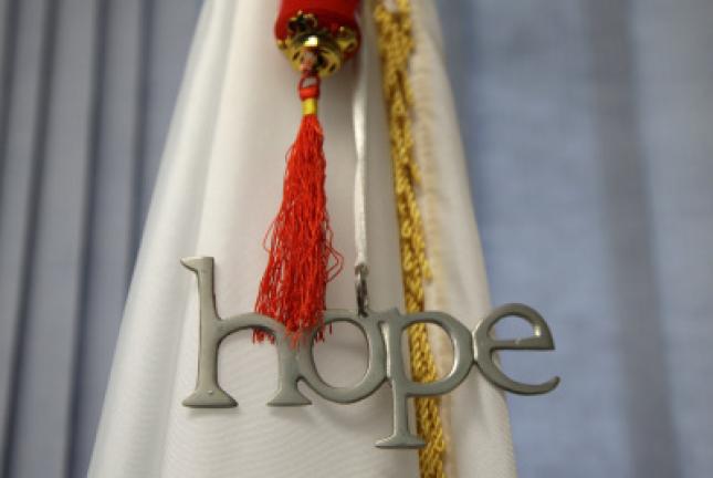 In this July 31, 2017 photo a medallion of the word hope hangs together with a Rhode Island state flag in the office of Barrington, R.I., Police Chief John LaCross, in Barrington. LaCross, who lost his brother to suicide in 1979, and has met with…