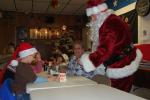 Two Santas meet across the table as Skylar Green dons his hat.