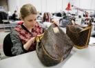 In this photo taken Wednesday, April 9, 2014, Jenna Starr inspects a pair of Louis Vuitton handbags to authenticate them and make sure they meet brand standards at the headquarters of The RealReal in San Francisco. An explosion of resale online…