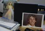 In this July 31, 2017 photo a photograph of Joseph LaCross, right, rests near an image of Jesus, left, on a desk belonging to Barrington, R.I., Police Chief John LaCross at the police station, in Barrington. Joseph LaCross committed suicide in 1979…