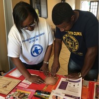 Romona teaches male participant Self-breast exam at Juneteenth celebration.
 Jun 16th