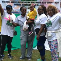 Liitle Egipt recieving her gift with Mom. From the left: Chichi O'Koli (Walkathon Chair), Nkechi Amaeze (NNAG President) and Bosede Balogun (NNAG Secretary) Cheering.
