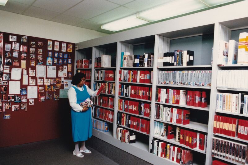 Circulation department member Antoinette "Toni" Shaw shelving videos in the audio-visual room.