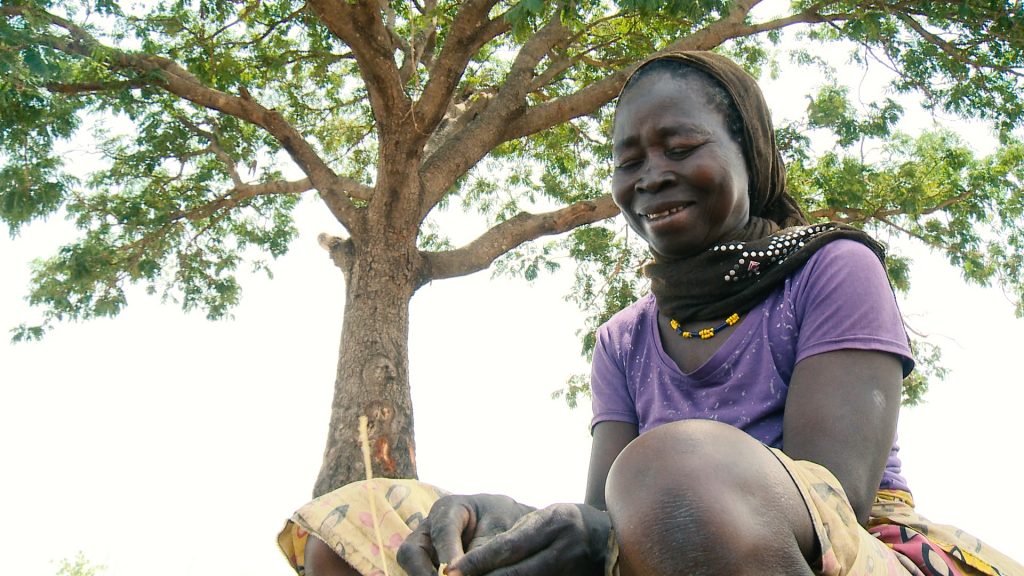 A woman removes the seeds from the pods of legumes grown in her field in southern Chad.