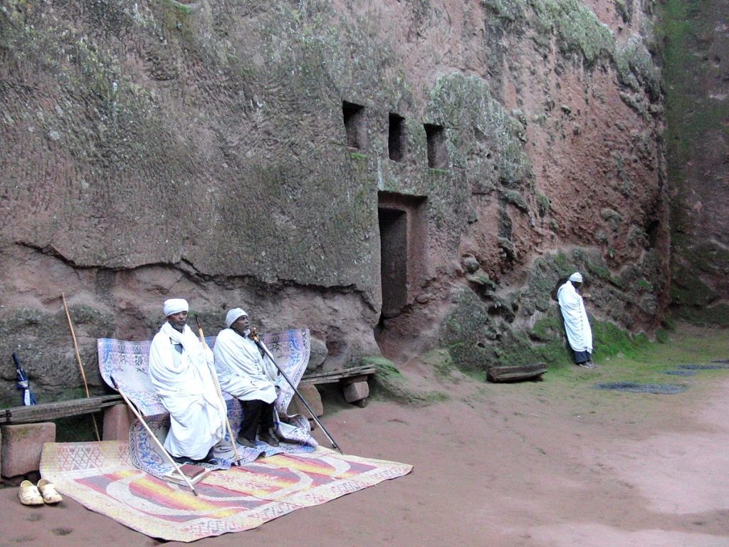 Monks sitting in front of the Bete Amanuel rock church in Lalibela, Ethiopia. (Photo credit: Jens Klinzing/Wikimedia Commons)