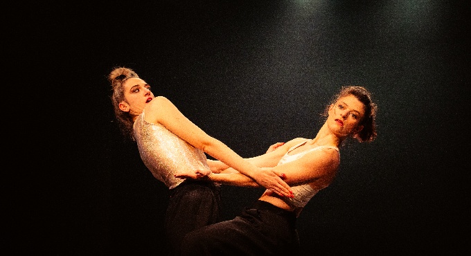 Dues noies agafant-se per la cintura com si estiguéssin assajant una coreografia.