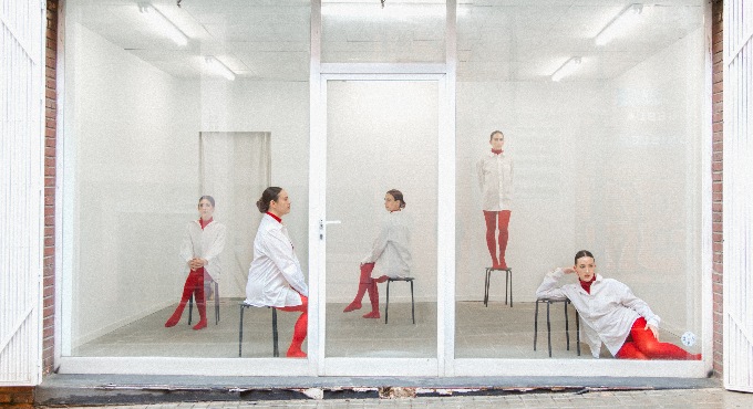 5 noies a darrera d'una vitrina com si fóssin maniquís. 