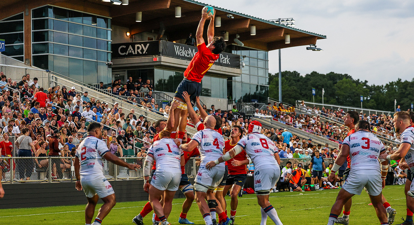 Saque de touche o lineout en rugby con un jugador español elevado en el aire atrapando el balón