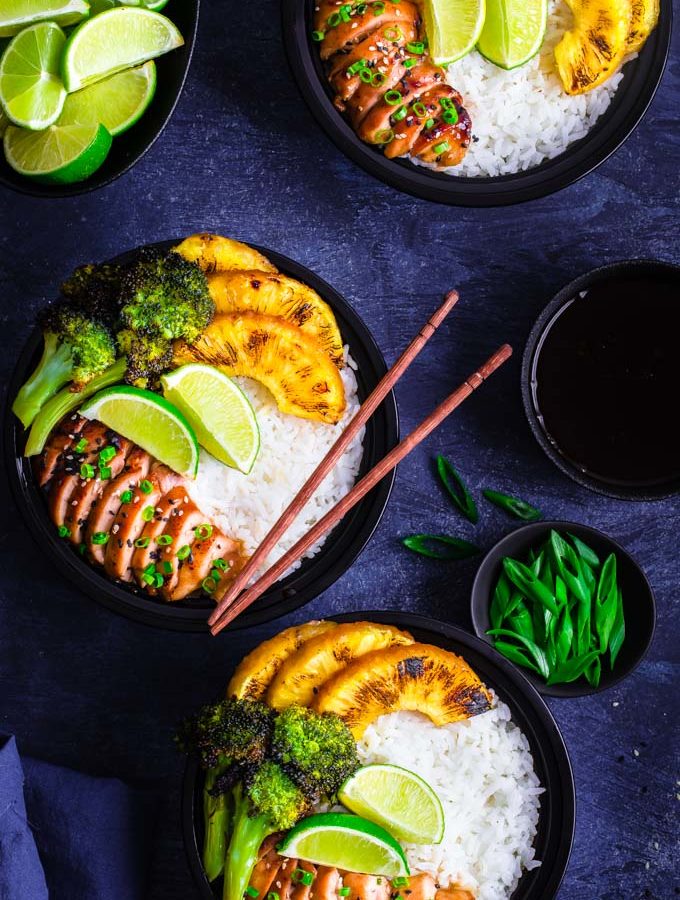 3 Bowls containing rice, teriyaki chicken, pineapple slices and broccoli florets.