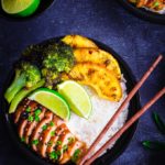 A bowl containing rice, teriyaki chicken, pineapple slices and broccoli florets.