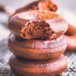 3 chocolate protein donuts stacked on a cooling rack.
