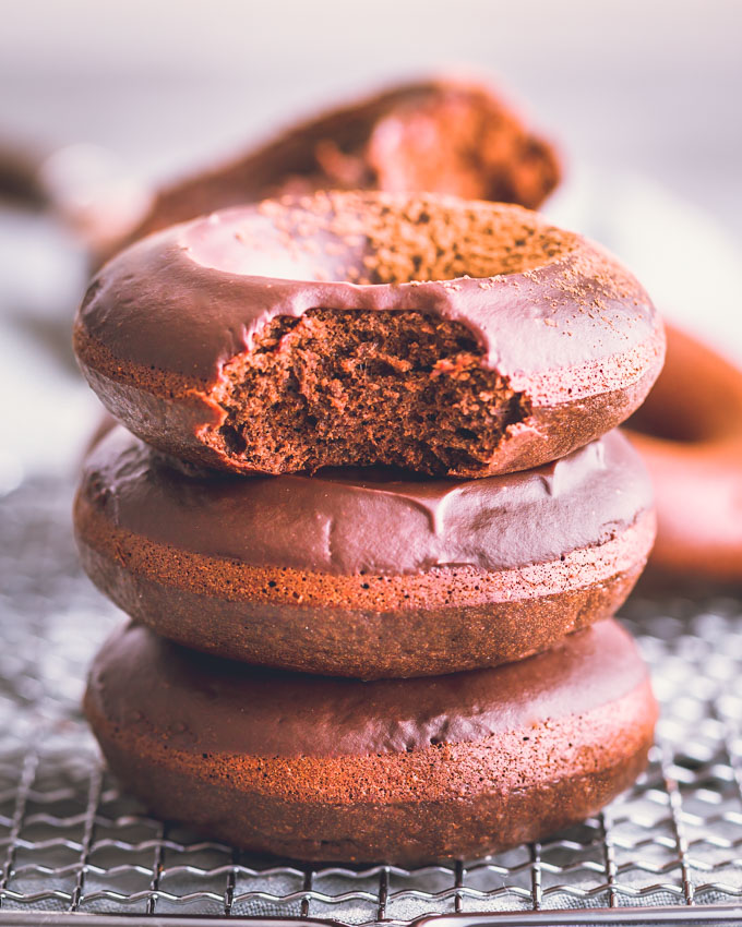 3 chocolate protein donuts stacked on a cooling rack.
