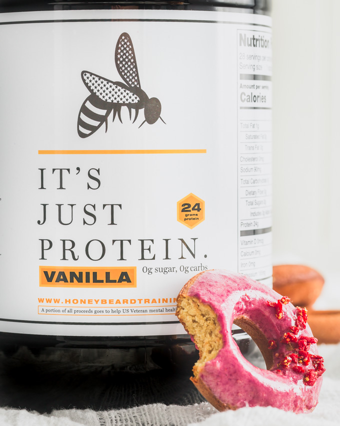 A vanilla whey protein tub with a protein donut.