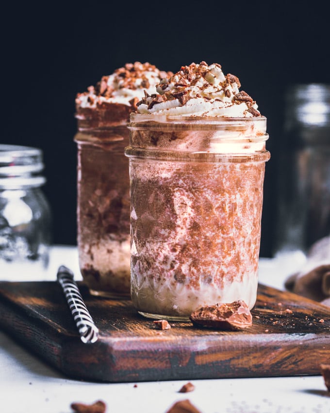 2 chocolate protein milkshake glasses on a cutting board