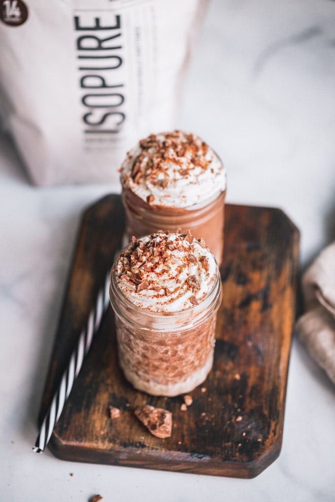 2 chocolate protein milkshake glasses on a cutting board