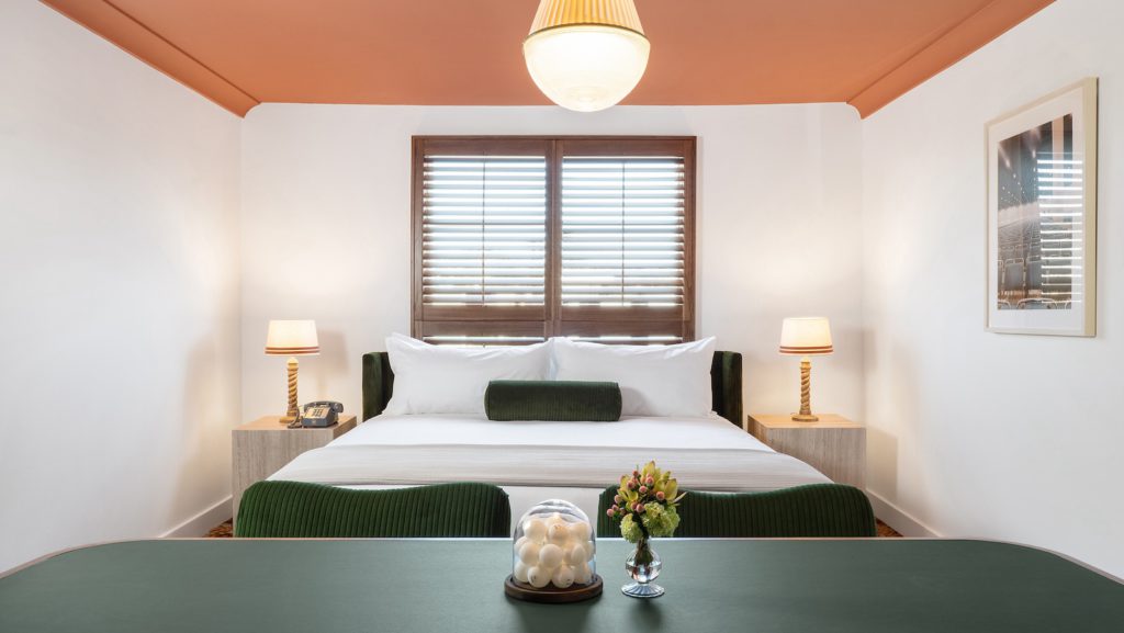 palihouse west hollywood - Long table and chairs with bed area behind it. Two night tables with lamps on either side of bed under window.