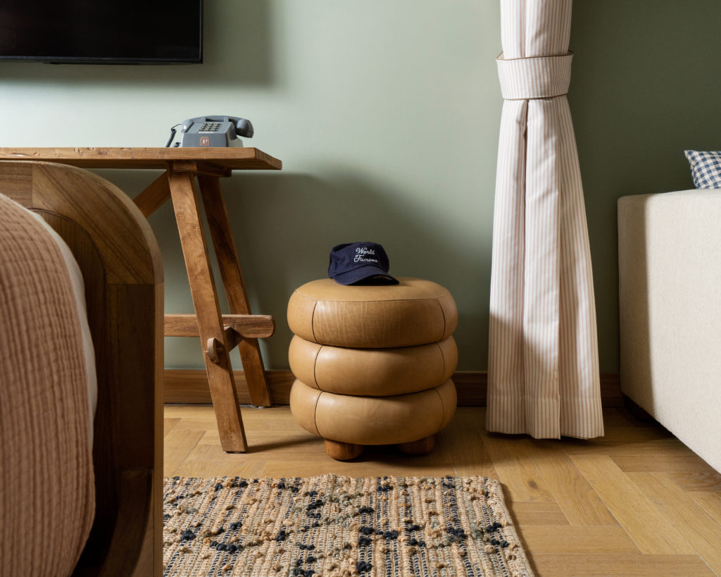 Palihouse Hyde Park Village - leather ottoman with branded hat, sitting on top, telephone on wooden table